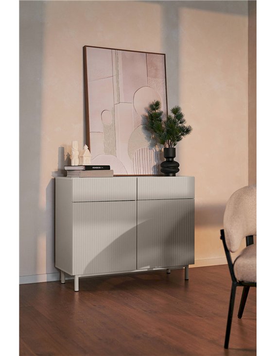 Commode beige rainurée en ambiance avec tableau et objets décoratifs