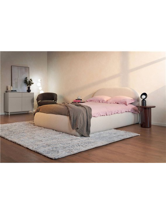 Commode beige rainurée dans une chambre près d'un lit et d'une table d'appoint
