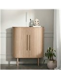 Commode haute rainurée claire dans un intérieur, avec bougie et plante en pot