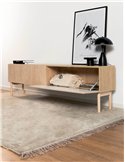 Meuble TV japandi en bois clair posé sur tapis beige avec cadre et lampe