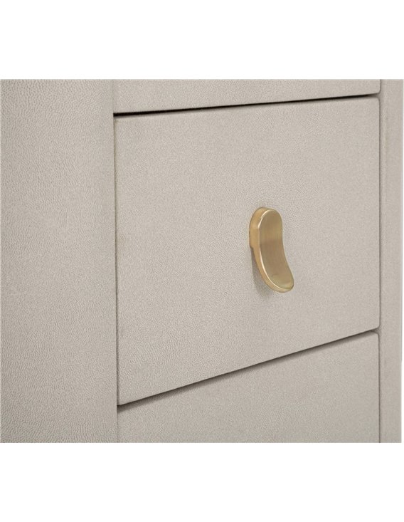 Détail d'une poignée dorée incurvée sur un tiroir beige