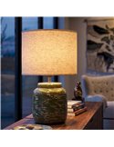 Lampe à poser verte allumée sur un meuble en bois devant une baie vitrée
