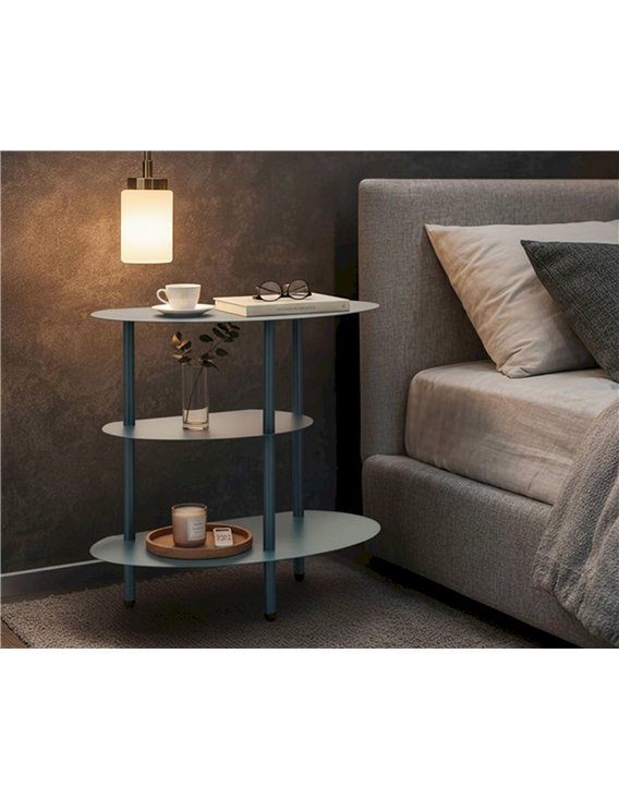 Table de chevet bleu canard dans une chambre avec lampe, livre et bougie