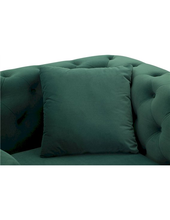 Coussin carré vert posé contre le dossier capitonné du fauteuil