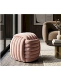 Pouf rose en velours sur un tapis, à côté d'une table basse noire et dorée