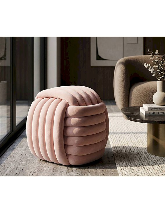 Pouf rose en velours sur un tapis, à côté d'une table basse noire et dorée