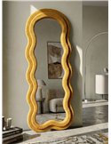Miroir ondulé jaune moutarde dans un salon, adossé au mur près d'un fauteuil