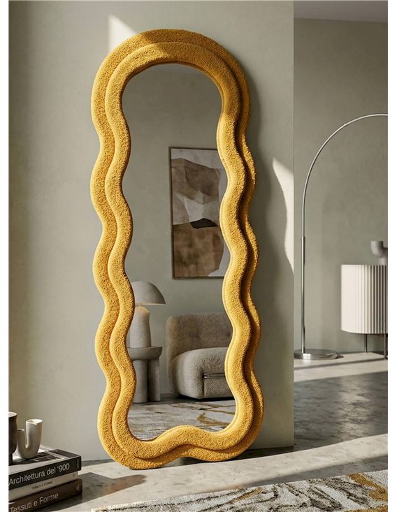 Miroir ondulé jaune moutarde dans un salon, adossé au mur près d'un fauteuil
