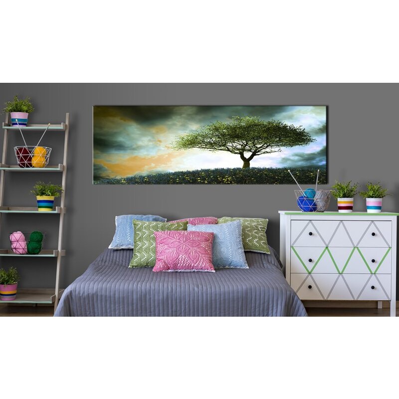 Tableau colline de malachite au-dessus d'un lit avec coussins colorés et commode blanche