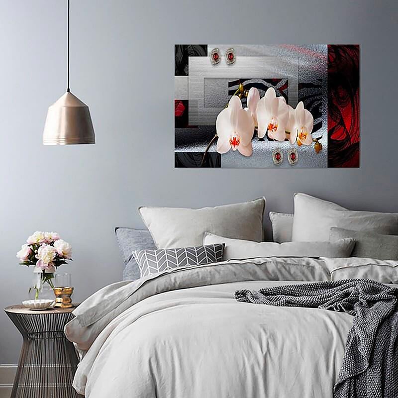 Tableau orchidée blanche accroché au-dessus d'un lit dans une chambre aux tons gris