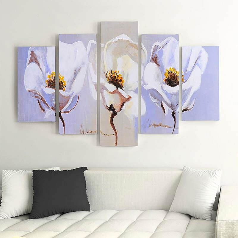Tableau trois fleurs blanches accroché au-dessus d'un canapé blanc et de coussins