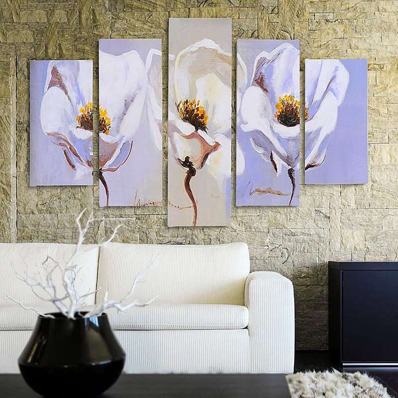 Tableau trois fleurs blanches au mur en pierre, près d'un canapé et d'un vase noir