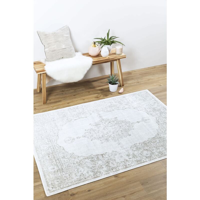 Tapis Isphahan posé sur parquet, à côté d'un banc en bois et d'objets déco