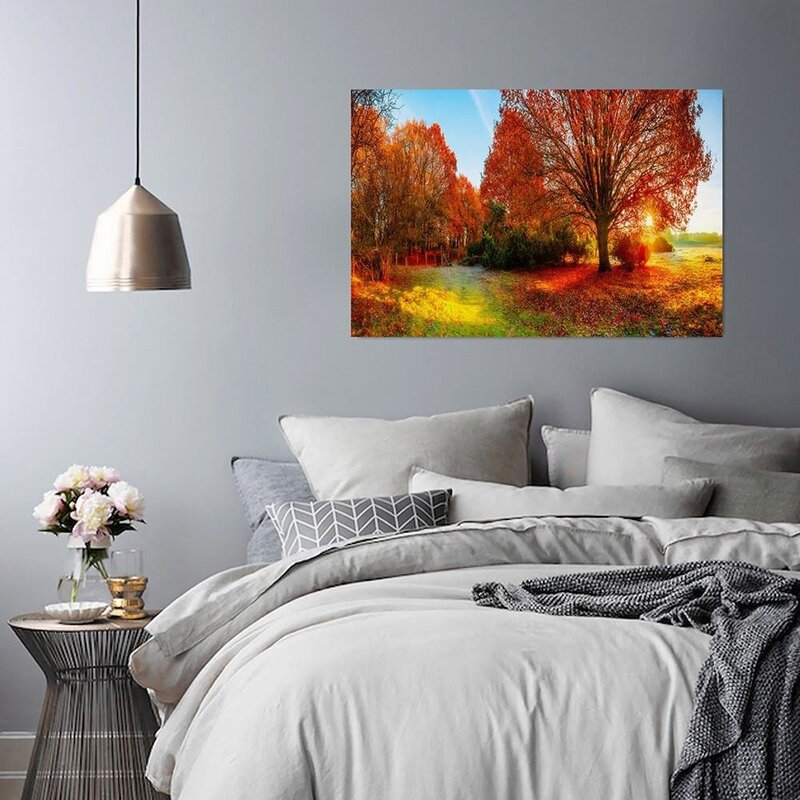 Tableau paysage d'automne accroché au-dessus d'un lit dans une chambre