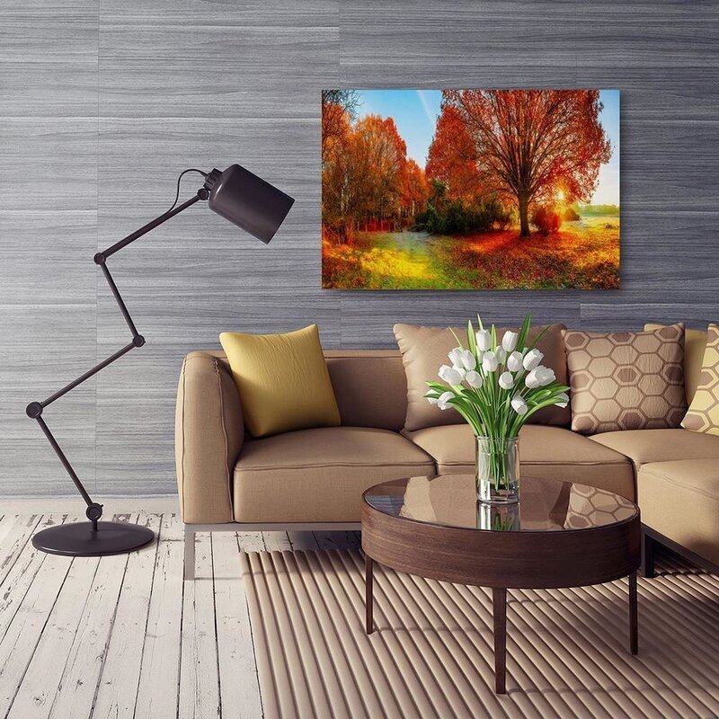 Tableau paysage d'automne au-dessus d'un canapé beige dans un salon