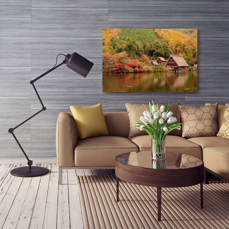 Tableau le paysage côtier au mur d'un salon, canapé beige, tulipes blanches et lampadaire noir au premier plan