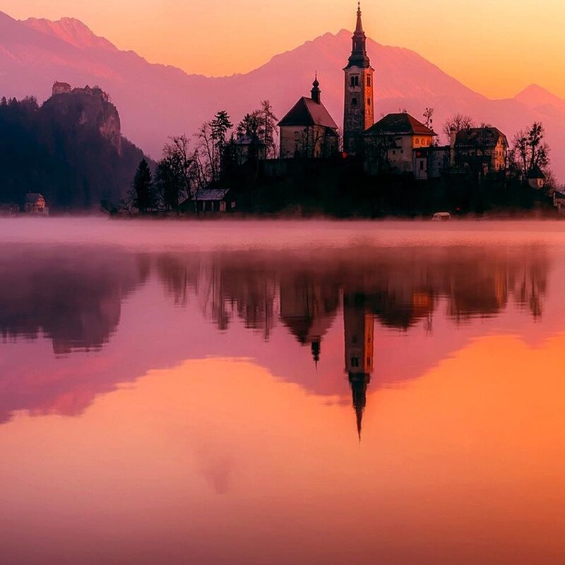 Tableau château sur un lac de montagne en gros plan, clocher et reflet au lever du soleil