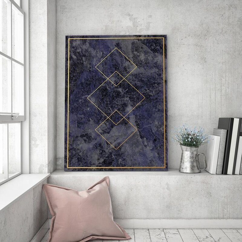 Tableau carrés d'or accroché au mur, au-dessus d'un coussin rose sur une banquette