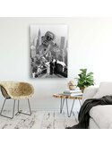 Tableau abstraction d'astronaute géant accroché au mur d'un salon clair, au-dessus d'un fauteuil en osier