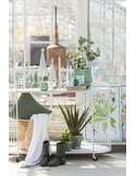 Plaid blanc posé sur une console blanche, entre plantes et bougies
