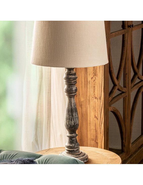 Lampe de salon posée sur une table ronde en bois, à côté d'un canapé vert