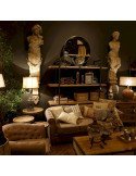 Lampe de salon dans un intérieur, entourée de statues, canapé et étagères