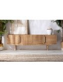 Meuble TV en bois clair posé sur un tapis, mur blanc et plantes de chaque côté
